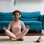 Woman sitting on the floor and meditating with closed eyes at home chronic joint pain